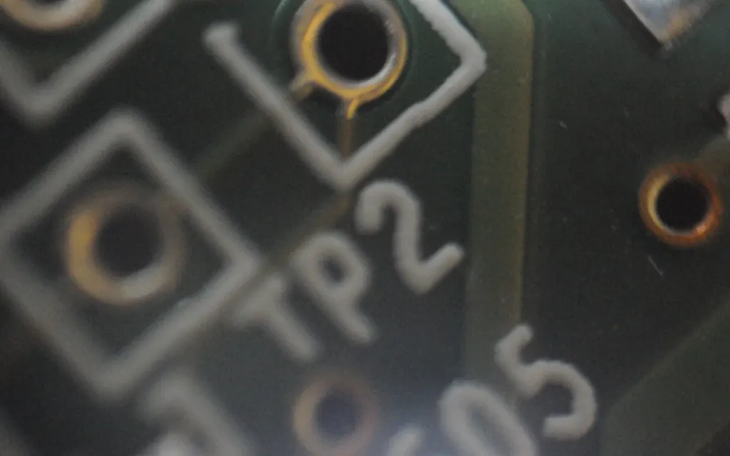 Close-up of a green printed circuit board with solder pads